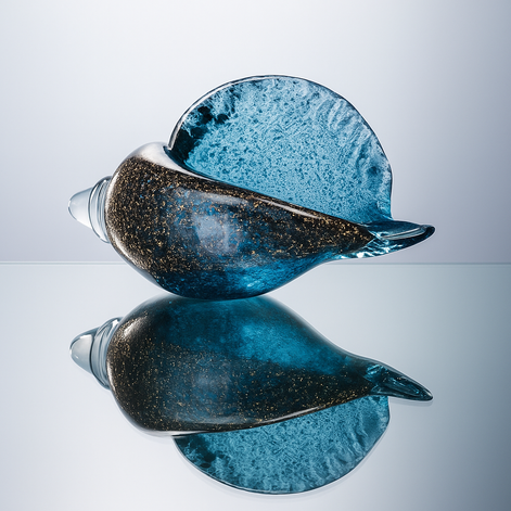 Luxury hand-blown blue glass conch with golden accents, placed on a reflective surface creating a mirror effect, artistic ocean-inspired home decor piece.