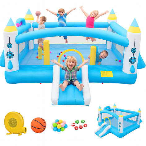 Children joyfully playing on a blue and white inflatable bounce house with rocket designs. One child slides down the small slide while others jump and throw a ball inside the play area. Below the bounce house, there are accessories including an air blower, a basketball, colorful plastic balls, and a mini version of the inflatable structure.